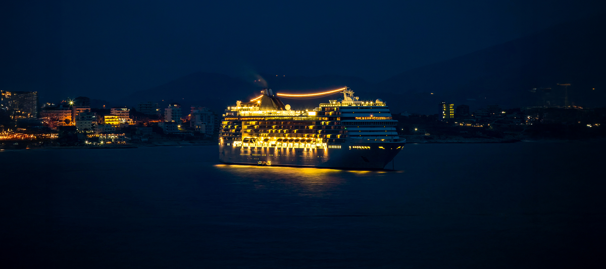 Beleuchtetes Kreuzfahrtschiff am Abend