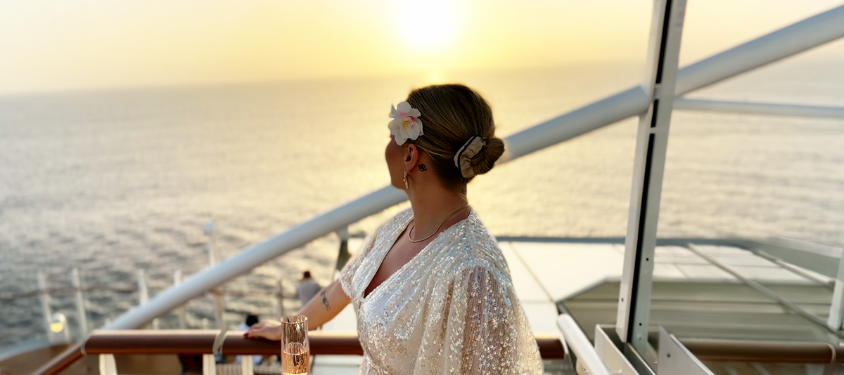 Frau steht bei Sonnenuntergang an Deck eines Schiffs