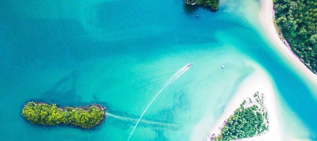 Boote beim Inselhopping entlang türkisblauem Meer und weißen Sandstränden