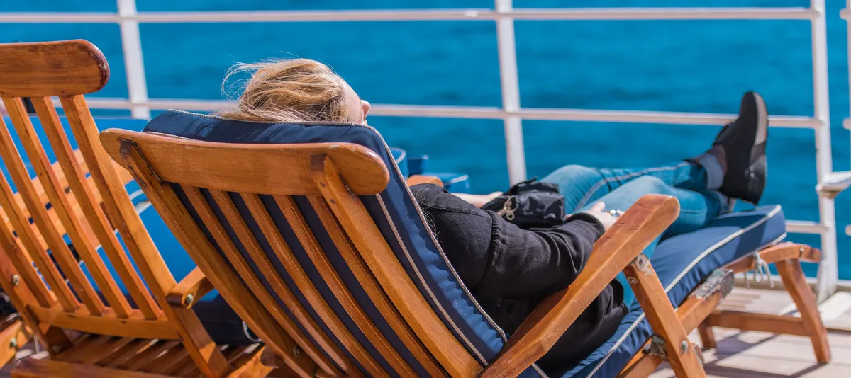Frau in Liegenstuhl auf Kreuzfahrtschiff
