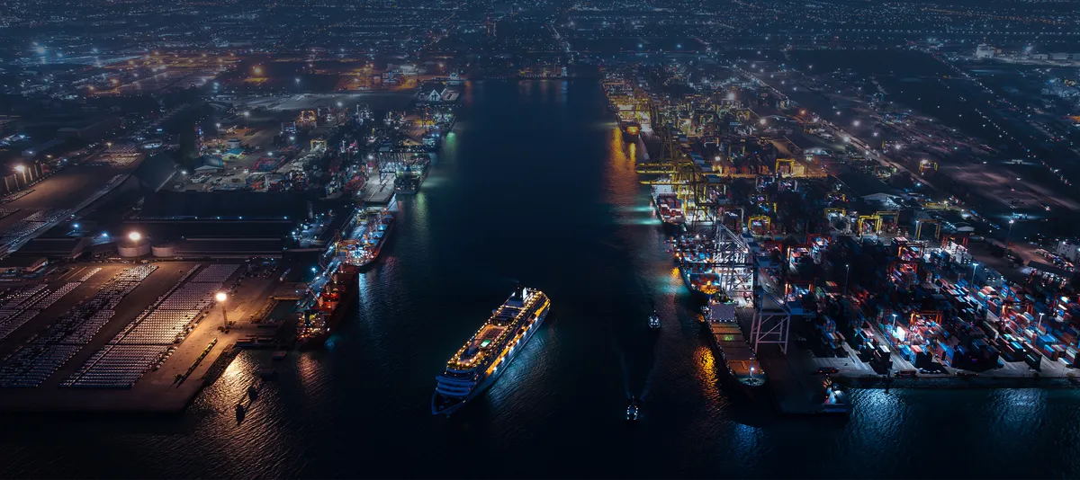 Kreuzfahrtschiff bei Nacht in beleuchtetem Hafen