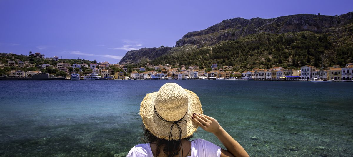 Frau mit Hut mit Blick auf das türkisblaue Meer