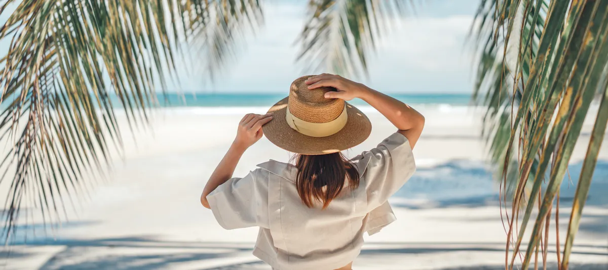 Frau am Strand zwischen Palmen