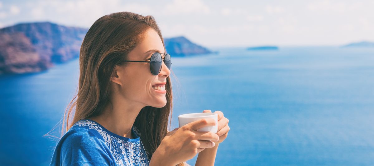 Frau mit Kaffee vor Meerblick